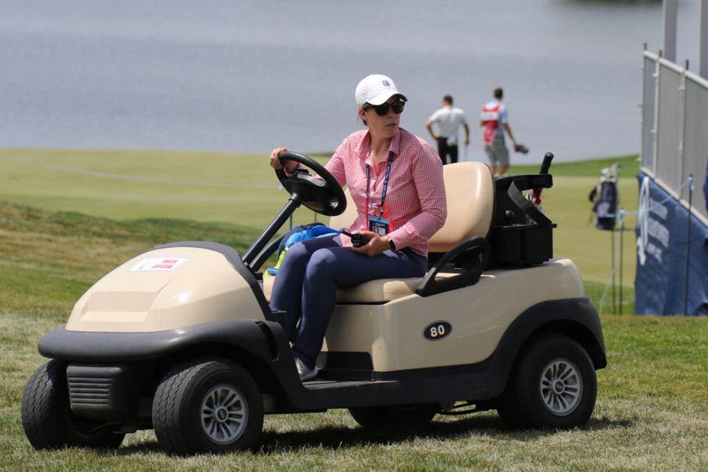Diana Lendl drives a golf cart on a golf course.