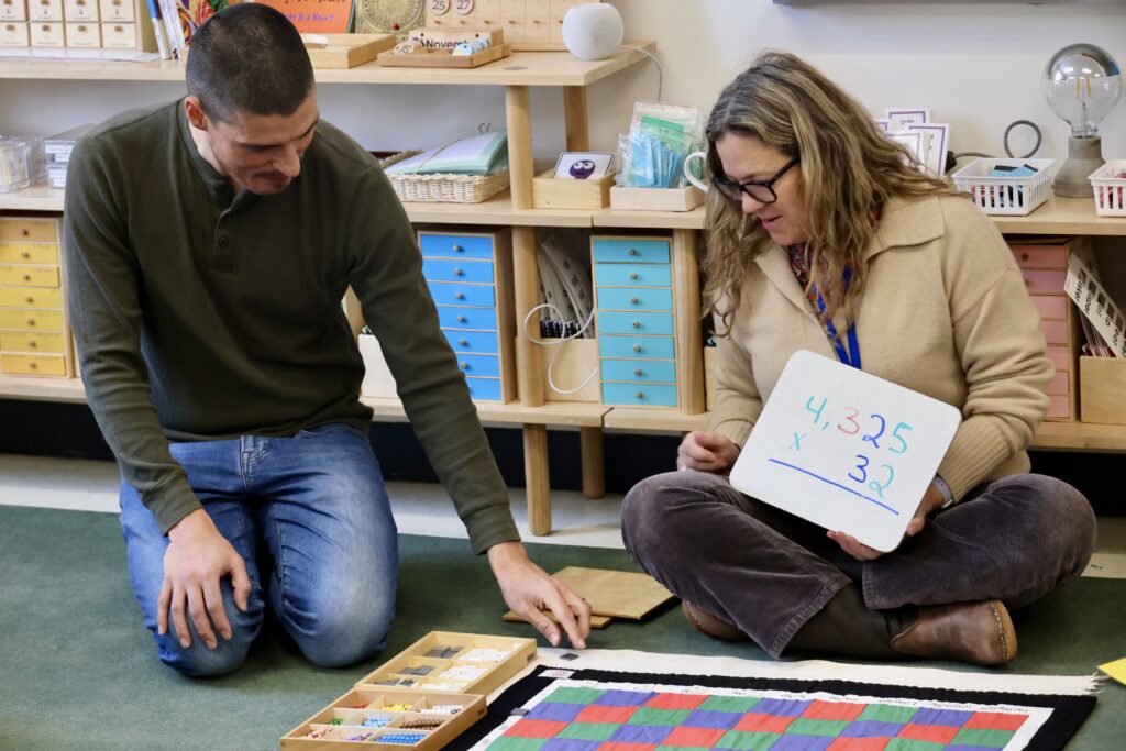 A Lower Elementary teacher gives a parent a long division lesson during The Voyage.
